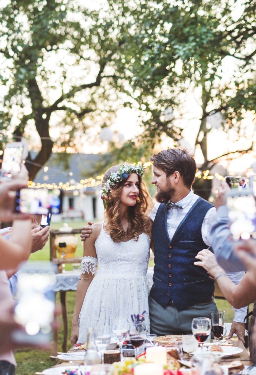 Guests with smartphones taking photo of bride and groom at wedding reception outside. Guests with smartphones taking photo of bride and groom at wedding reception outside.